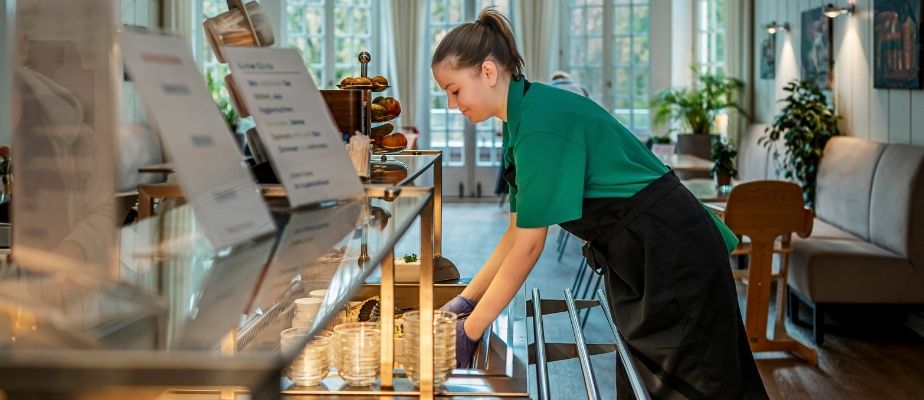 Eine junge Mitarbeiterin füllt das Salatbuffet im Speisesaal auf.