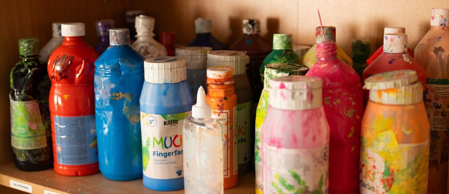 Mehrere Flaschen mit vielen verschiedenen flüssigen Farben darin stehe in einem Regal.