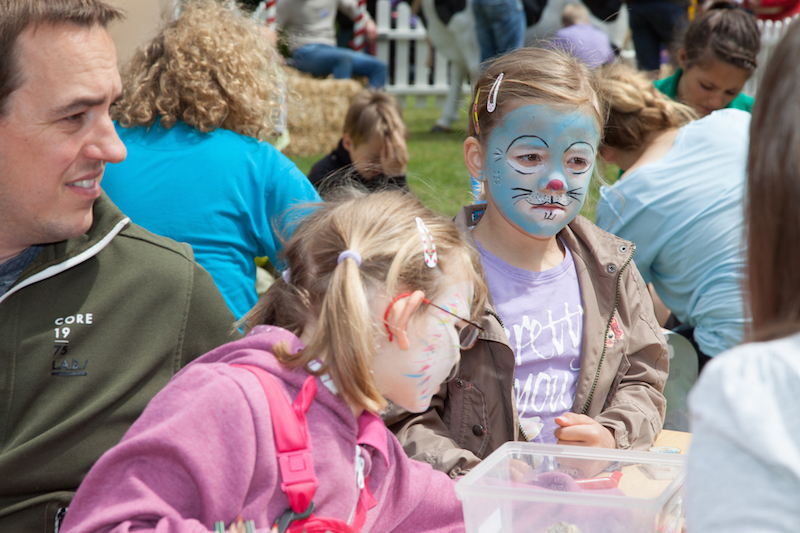 Zwei Mädchen mit Gesichtsbemalung, die an einem Tisch sitzen.