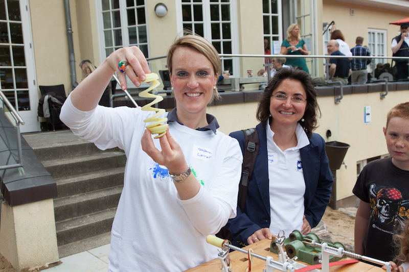 Eine Frau hält eine spiralförmig geschnittene Kartoffel in der Hand, während eine andere Person neben ihr steht.