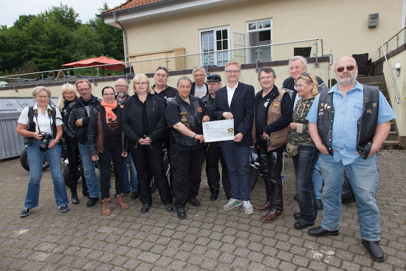 Eine Gruppe von Motorradfahrern posiert für ein Foto bei einer Veranstaltung im Freien.