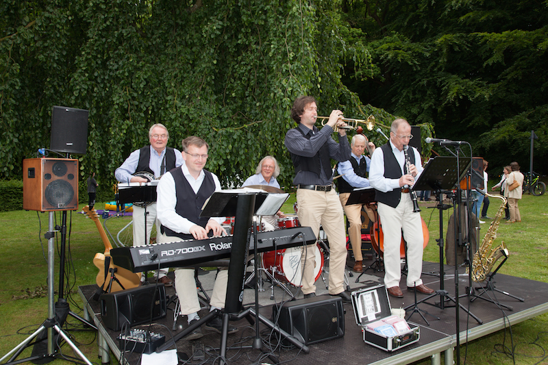 Eine Musikgruppe mit mehreren Musikern, die auf einer Bühne im Freien spielt.