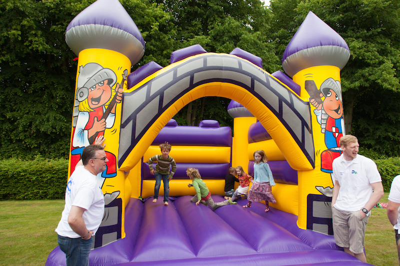 Bunte Luftkissenburg mit zwei Türmen und Comicfiguren auf den Seiten, Kinder spielen darauf.