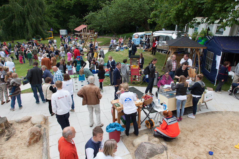 Menschenmenge bei einer Veranstaltung im Freien mit Ständen und Aktivitäten.