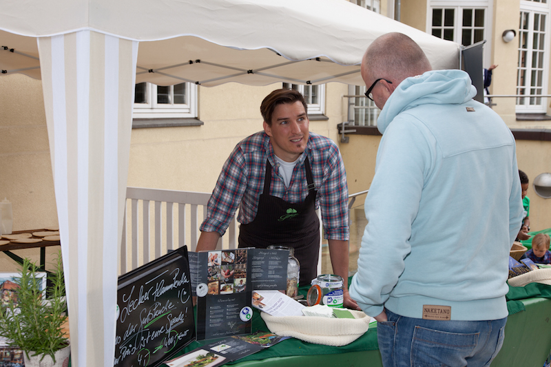 Ein Verkäufer im Marktstand spricht mit einem Kunden.