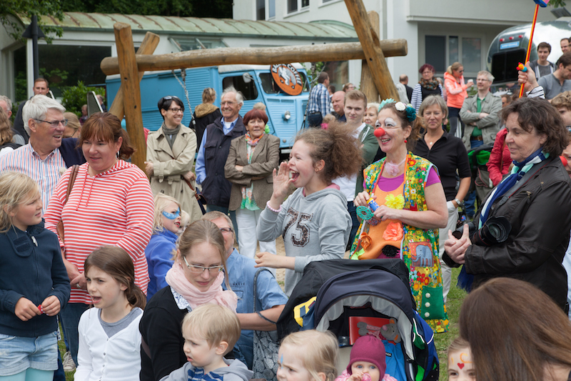 Eine Gruppe von Menschen, darunter Kinder und Erwachsene, versammelt sich bei einer Veranstaltung im Freien.