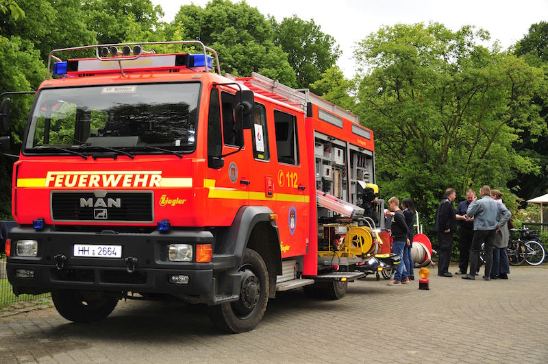 Rotes Feuerwehrfahrzeug der Marke MAN mit der Aufschrift 'FEUERWEHR' und der Notrufnummer '112'.