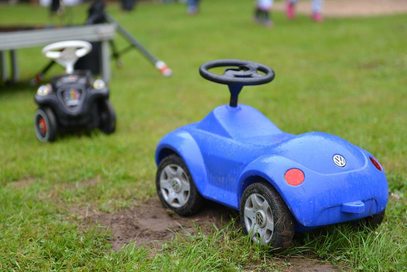 Blauer Kunststoffspielzeugwagen mit Volkswagen-Logo auf einem grünen Rasen.