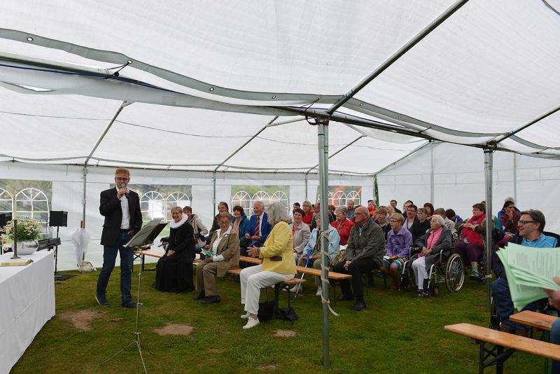 Ein Redner spricht vor einem Publikum in einem Zelt während einer Veranstaltung.