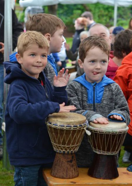 Zwei Kinder spielen auf Trommeln während eines Festes im Freien.