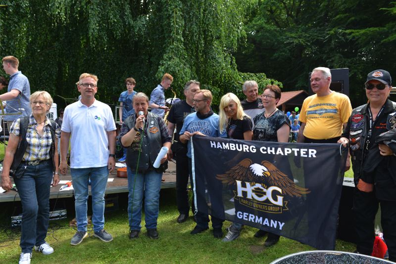 Gruppe von Personen, die ein Banner des Hamburg Chapter der Harley Owners Group halten.