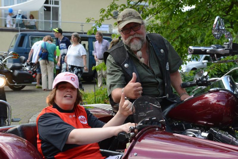 Ein Junge und ein Mann geben Daumen hoch in einem roten Motorradgespann.