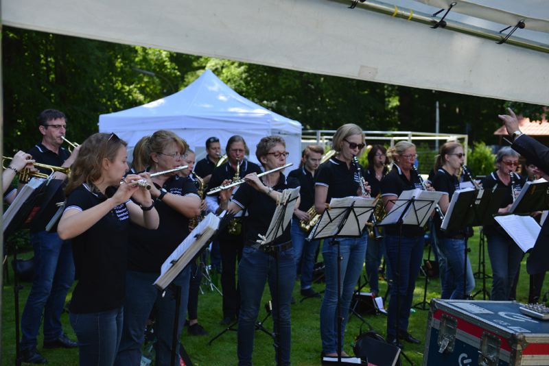 Ein Blasorchester spielt auf einer Veranstaltung im Freien mit verschiedenen Instrumenten.