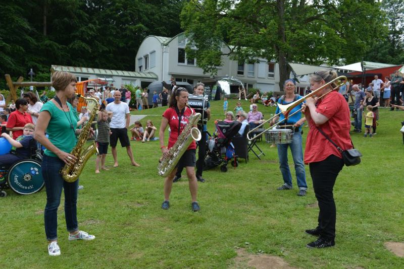 Vier Musikerinnen spielen verschiedene Instrumente während eines Sommerfestes im Freien.