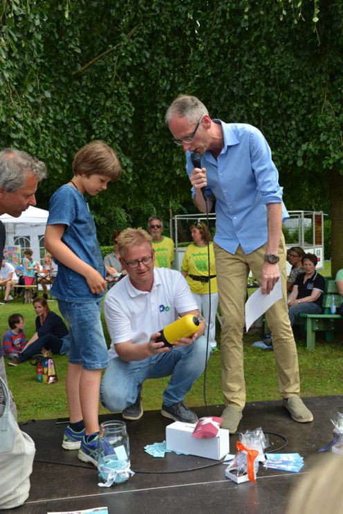 Drei Männer und ein Junge auf einer Bühne während einer Veranstaltung, einer spricht ins Mikrofon.