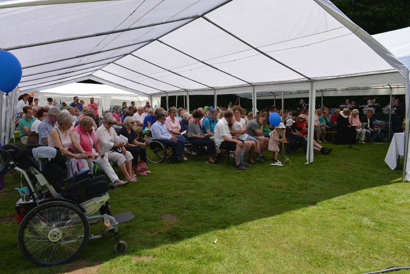 Menschen sitzen in einem Zelt während einer Veranstaltung.