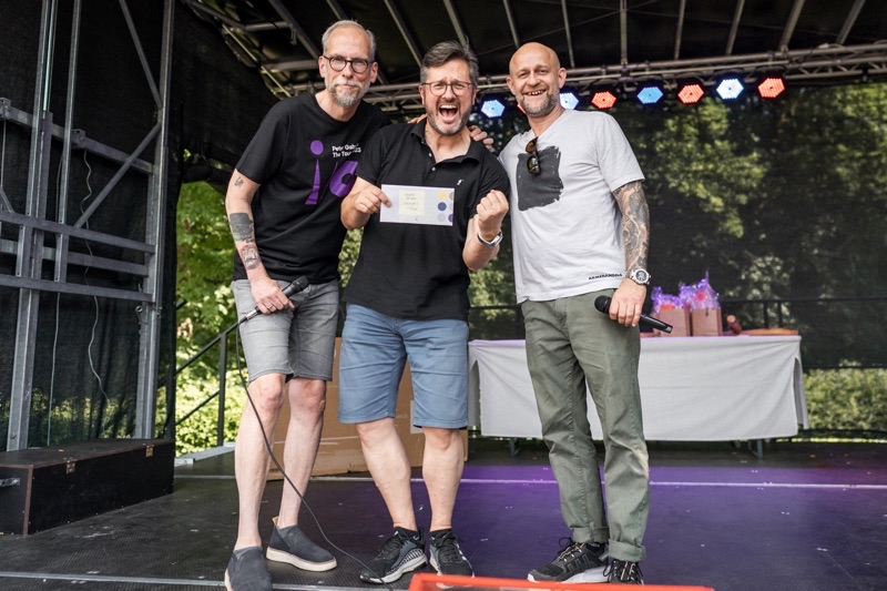 Drei Männer stehen auf einer Bühne und halten einen Preis in der Hand.