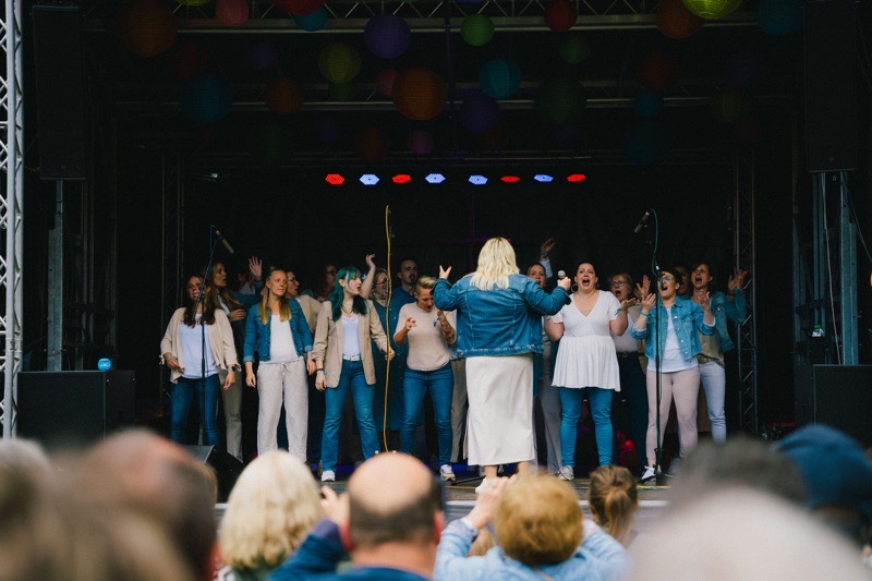 Eine Gruppe von Sängerinnen auf einer Bühne mit bunten Lampions im Hintergrund.