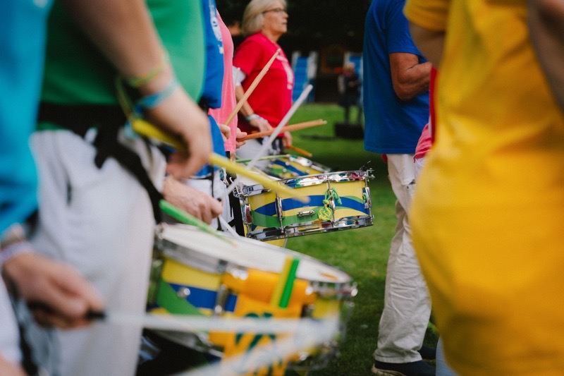 Trommler:innen halten Trommeln in verschiedenen Farben und spielen mit Stöcken im Freien.