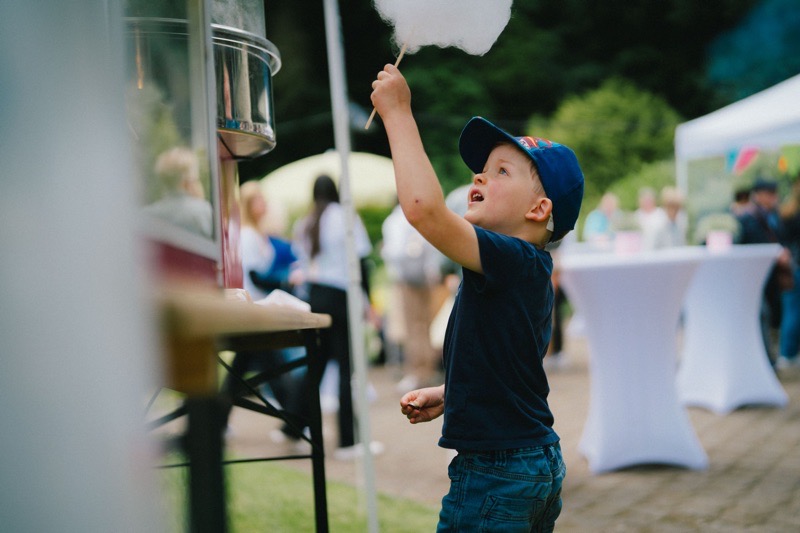 Ein Junge mit blauer Mütze hält eine Zuckerwatte.
