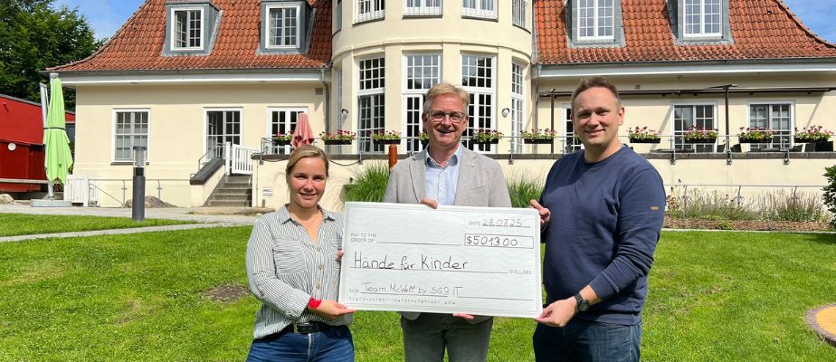 Gasteltern übergeben eine Spende für Kinder mit Behinderung an Geschäftsführer Steffen Schumann vor dem Neuen Kupferhof.