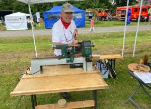 Ein Mann bedient eine Drechselmaschine auf einer Veranstaltung im Freien.