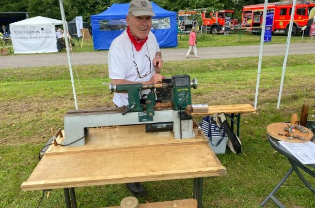 Ein Mann bedient eine Drechselmaschine auf einer Veranstaltung im Freien.