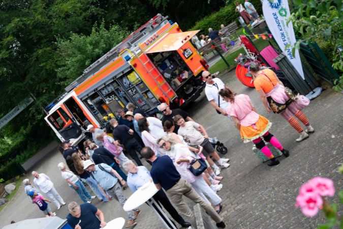 Eine Gruppe von Menschen steht vor einem Feuerwehrauto während einer Veranstaltung im Freien.