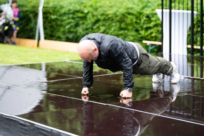 Mann führt Liegestütze auf einer nassen Bühne im Freien durch.