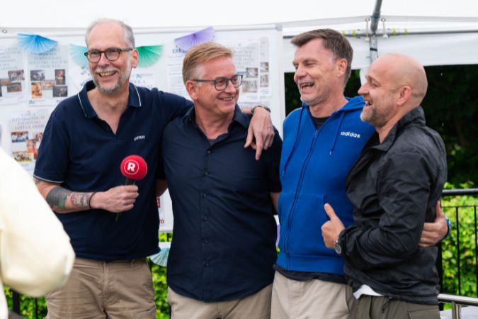 Vier Männer posieren lachend für ein Foto.