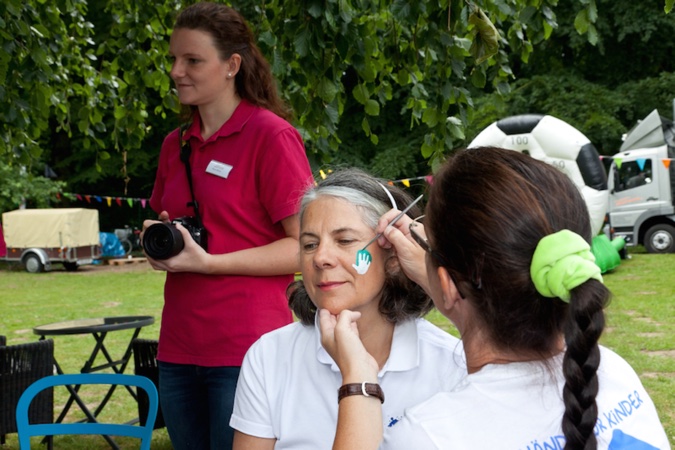 Eine Frau malt einer anderen Frau eine Hand auf die Wange.