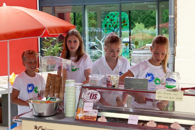 Vier Kinder stehen an einem Eisstand.