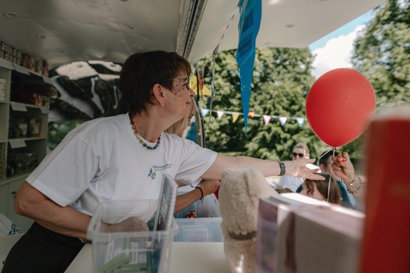 Eine Frau reicht einen roten Ballon von einem Verkaufsstand aus.