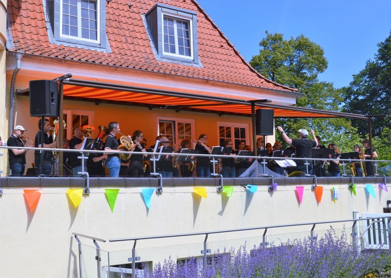 Ein Musikensemble spielt auf einer Terrasse unter einer Markise.