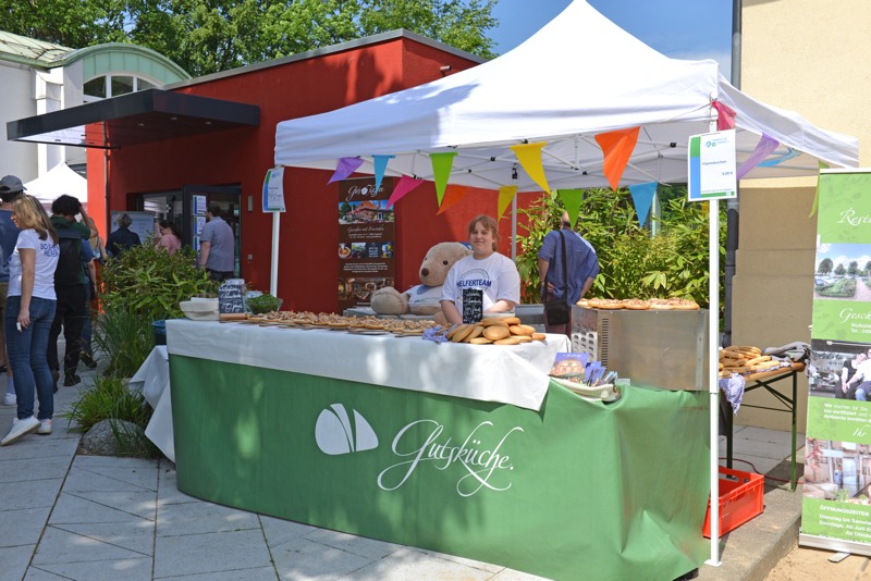 Ein Verkaufsstand mit verschiedenen Gebäcksorten und einer Person, die hinter dem Tisch steht.