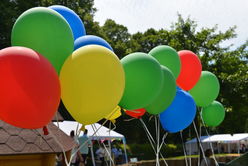 Bunte Luftballons in den Farben Grün, Blau, Rot und Gelb, die an Schnüren hängen.