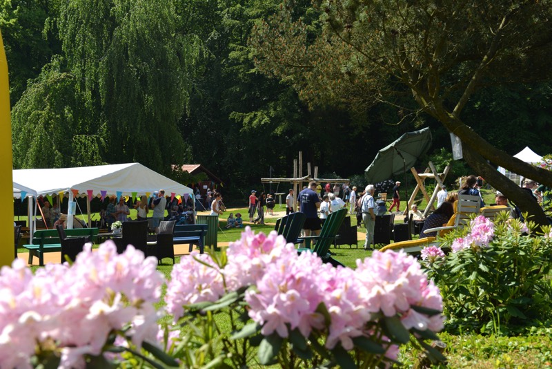 Menschen auf einem Sommerfest im Freien mit bunten Dekorationen und Ständen.
