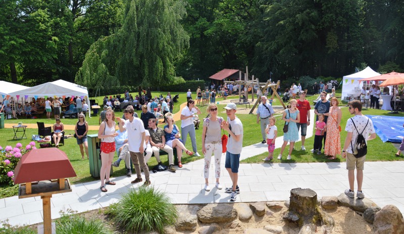 Menschenmenge bei einem Sommerfest im Freien mit Zelten und Aktivitäten.