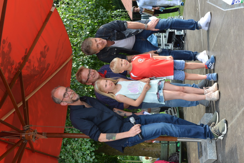 Gruppenfoto von zwei Erwachsenen und zwei Kindern, die unter einem roten Sonnenschirm stehen.