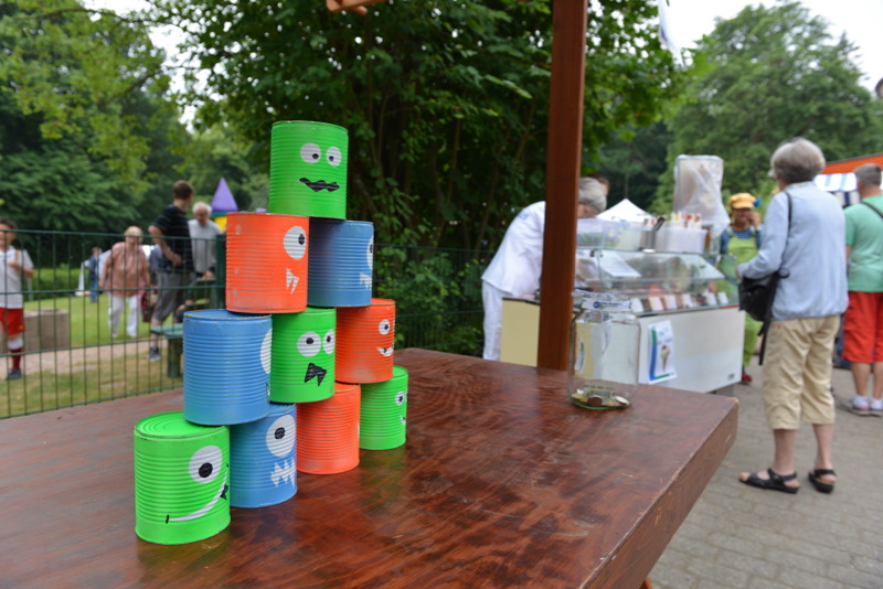 Ein Stapel aus bunten Dosen in verschiedenen Farben mit aufgemalten Gesichtern auf einem Tisch.