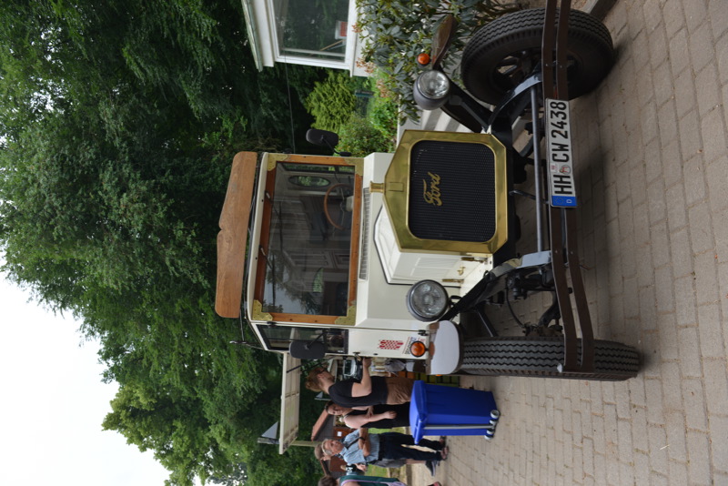 Ein historischer Ford mit Holzverkleidung, der auf einem gepflasterten Weg steht.