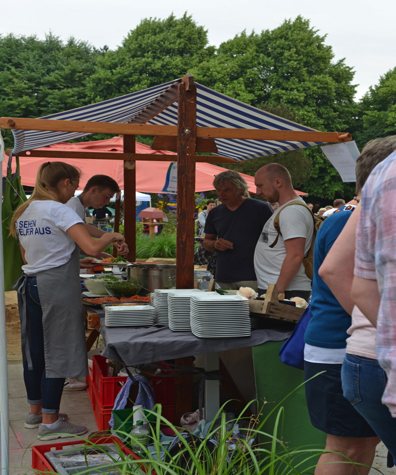 Ein Essensstand mit einer Bedienung, die Gerichte zubereitet, während Kunden warten.
