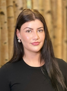 Portrait junger Frau mit dunklen langen Haaren vor Bambusstangen-Wand.