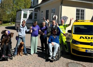 Beim Kinder-Lebens-Lauf 2026 winken Menschen vor gelbem ADAC-Auto mit Engelsfackel im Neuen Kupferhof.