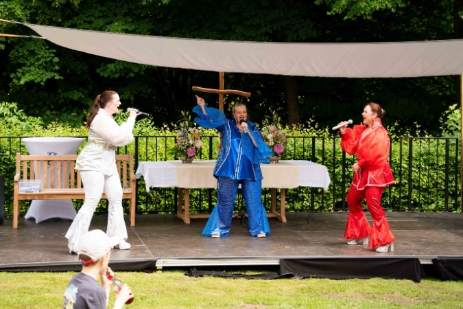 Drei Sängerinnen in 70er-Jahre Outfits stehen auf der Bühne und performen zu den Songs von ABBA.