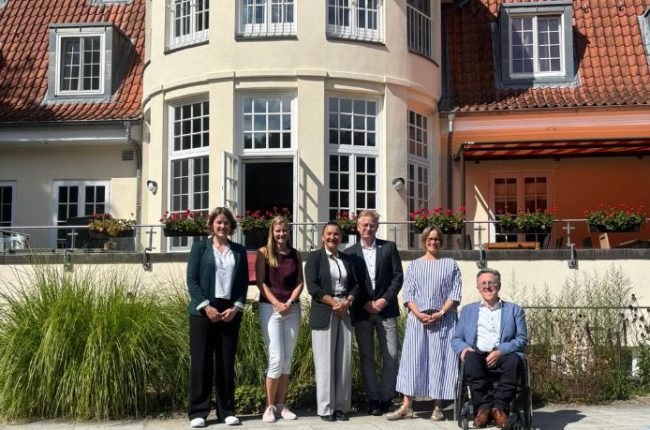 Vor dem Neuen Kupferhof stehen sechs Personen. Von links nach rechts sind Gesche Emme, Viola Hellwege, Funda Gür, Steffen Schumann und Hans Nee zu sehen.
